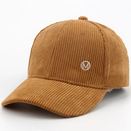 Diamond-studded M-letter corduroy baseball cap in solid color with adjustable strap, unisex streetwear headwear by VOIDWEAR.. Brown corduroy cap with a logo on a white background
